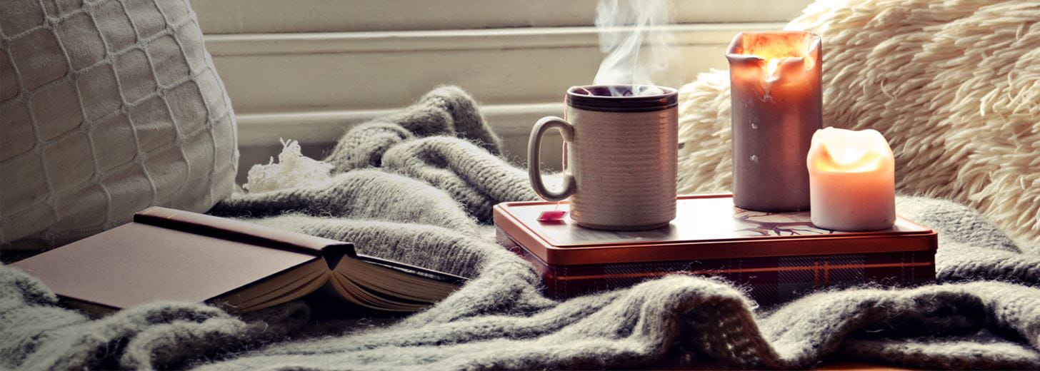 Steaming cup of coffee on the arm of a sofa